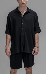 Camisa de manga corta con cuello solapa, confeccionada en lino. Presenta un corte oversize y cierre frontal con botones.