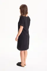Vestido corto de lino color negro, con escote en V, manga corta y bolsillos laterales, destacado por costuras a contratono en color blanco.