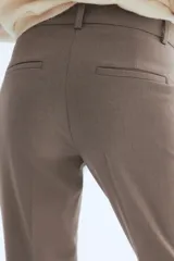 Pantalón tobillero de tejido elástico, color gris topo, con cintura estándar y elástico oculto. Presenta bolsillos al bies y bolsillos traseros decorativos.