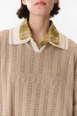 Sweater de punto color marrón con cuello polo en contraste color crema. Presenta diseño de rayas verticales texturizadas, mangas largas con puños en color crema y corte holgado.