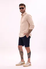 Camisa de manga larga color beige, con cuello clásico y botones frontales.