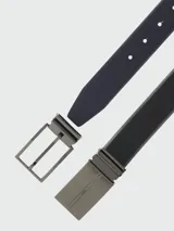 Cinturón reversible de cuero negro con hebilla metálica rectangular de diseño minimalista y cierre de pasador.