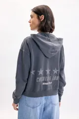 Campera deportiva con capucha y cierre frontal, de color gris con efecto acid wash. Presenta bolsillos tipo canguro, estampa con la inscripción 'Creative Lab' y detalles de pequeñas estrellas en el pecho.