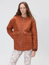 Campera reversible capitoneada con cierre frontal. Un lado es de color negro y el otro es de color beige, ambos con diseño acolchado. Cuenta con cuello redondo, mangas largas y bolsillos laterales.