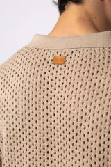 Camisa de manga corta tejida en algodón con diseño calado, cuello tipo bowling y cierre frontal con botones al tono.