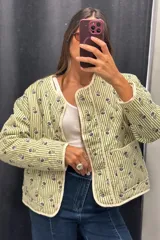 Cazadora capitoneada de corte recto, con diseño de rayas verticales verdes y estampado floral. Presenta cuello redondo, cierre frontal con botones y bolsillos laterales de parche.