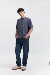 Remera de manga corta color marrón, con ajuste regular y escote redondo. Presenta un estampado frontal con texto en blanco formando un diseño circular.