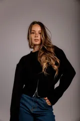 Suéter de punto color crema, con cuello redondo, manga larga y cierre frontal parcial que deja ver parte del abdomen.