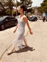 Vestido tejido en lurex color plateado, con diseño geométrico en cuero en el frente y flecos en el ruedo. Breteles finos de cuero con tientos plateados.