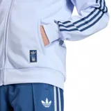 Campera deportiva Adidas de la Selección de Italia, color celeste, con cierre frontal y las clásicas tres tiras en azul marino en las mangas. Cuenta con bolsillos laterales, cuello alto y los escudos de Adidas y de la federación italiana bordados en el pecho.