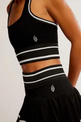 Conjunto deportivo compuesto por un top halter y una pollera pantalón de color blanco con líneas horizontales verdes.