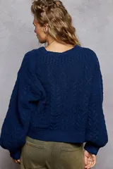 Sweater de tejido de punto trenzado en color azul profundo, con diseño cropped y cuello redondo. Presenta un parche central bordado con el diseño de una bandera estadounidense.