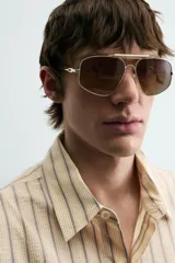 Camisa de algodón de corte relajado, color beige con finas rayas verticales en tonos gris y amarillo. Presenta cuello solapa, manga larga con puños abotonados y bajo con aberturas laterales.