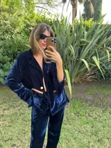 Blazer de terciopelo azul marino con solapas clásicas, cierre frontal de un botón y bolsillos con detalles en cuero color suela.
