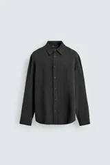 Camisa de corte regular confeccionada en tejido fluido con mezcla de lyocell, cuello solapa, manga larga con puños abotonados y cierre frontal de botones.