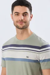 Remera de algodón y poliéster color verde militar con diseño de rayas horizontales en tonos azules, blancos y celestes en la parte superior del pecho. Cuenta con cuello redondo y mangas cortas.
