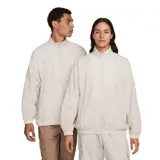 Chaqueta Nike Sportwear Essential Windrunner de color beige, diseño oversize con cierre frontal completo y cuello alto. Confeccionada en tejido arrugado ligero con forro de malla, presenta el logotipo de la marca bordado en el pecho.