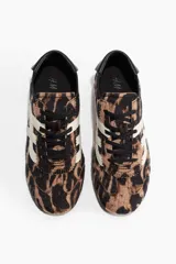 Calzado deportivo con cordones, diseño de estampado animal print de tigre y detalles en blanco y negro, con suela de goma acanalada.