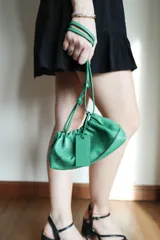 Cartera tipo sobre de cuero color fucsia, con diseño fruncido y cierre de cordón. Incluye una correa ajustable y extraíble para usarla como cartera o como sobre de fiesta.