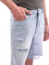 Bermuda de jean corte recto en color celeste claro, con diseño desgastado y roturas localizadas en los muslos y ruedos deshilachados.