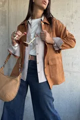 Chaqueta de gamuza color camel, con corte recto, cuello camisero, cierre frontal con botones metálicos y bolsillos frontales con solapa.