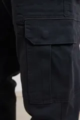 Pantalon cargo de corte recto en color verde militar, confeccionado en sarga de algodón con elastano. Presenta bolsillos laterales con fuelle y tapa, además de bolsillos traseros con cierre de botón.