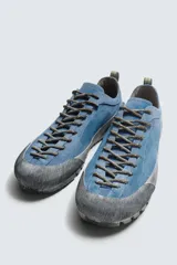 Zapatilla de cordones con diseño de inspiración montañista, confeccionada en piel con acabado de serraje en color azul. Presenta una puntera y refuerzo lateral en gamuza gris con textura desgastada, horma redonda y suela de goma dentada VIBRAM®.