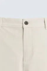Pantalón chino de corte slim fit, confeccionado en tejido elástico. Presenta bolsillos frontales, bolsillos traseros de vivo con botón y cierre frontal con cremallera y botón.