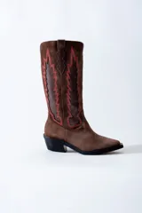 Bota texana de cuero negro con apliques de cuero marrón en los laterales y pespuntes en color crema. De caña media/alta y taco bajo. Diseño calado con motivos geométricos.