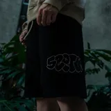 Bermuda negra de algodón con cordón ajustable en la cintura y parche bordado con el logo "SEPTUM" en el lateral.