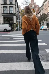 Pantalón de tiro alto color bordó, con pinzas delanteras, bolsillos frontales y falsos bolsillos con solapa en la espalda. Tiene pernera ancha y cierre frontal con cremallera, botón interior y gancho.