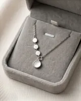 Collar de plata con cadena de eslabones finos y diseño asimétrico que incluye tres pequeños discos metálicos y un dije circular principal con incrustación de nácar.