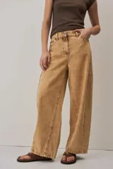 Jeans de corte barrel en color tostado, con diseño de perneras curvadas y costuras pespunteadas.