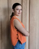 Chaleco de tejido de punto color naranja quemado, sin mangas, con cuello redondo y botones decorativos en el lateral.