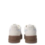 Championes Puma Karmen II Idol SD de estilo urbano, confeccionados en gamuza premium color beige. Presentan un diseño robusto con plataforma alta de color marrón y el logo de la marca en un tono celeste suave en el lateral.