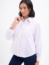 Camisa blanca de manga larga con cuello camisero, cierre frontal con botones y detalles de tablas verticales en el frente.