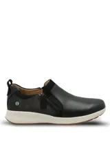 Zapatillas slip on Hush Puppies modelo Spinal Slip On, color negro, confeccionadas en cuero con detalles de gamuza y cierre lateral decorativo. Poseen suela blanca y base de goma con tecnología TripleDensity para mayor amortiguación y soporte.