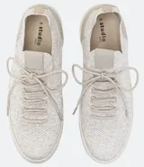 Zapatillas deportivas de punto color gris claro, con cierre de cordones y suela blanca.