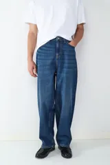 Jean de corte baggy con silueta holgada y relajada. Confeccionado en denim de tono azul oscuro con efecto lavado, cuenta con cinco bolsillos, cintura con trabillas y cierre frontal de botón y cremallera.