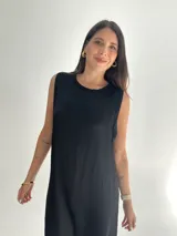 Vestido negro largo de tela satinada, sin mangas y con cuello redondo.