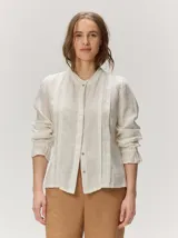 Camisa Diana de lino liviano color blanco, con silueta relajada, cuello mao, alforzas verticales en el frente, mangas con volumen y puños elastizados con volados.