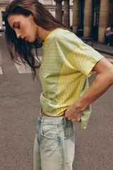 Camiseta de corte regular fit, cuello redondo y manga corta, confeccionada en una mezcla de algodón y lino. Presenta un diseño a rayas horizontales en tonos verdes y amarillos, con paneles laterales y mangas que combinan rayas verticales.