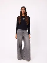 Jean de corte wide leg con diseño de pata ancha y costuras laterales visibles. Presenta un lavado azul clásico con efecto desgastado y cierre frontal con botón y cremallera.