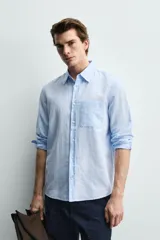 Camisa regular fit de manga larga con diseño a rayas verticales celestes y blancas. Cuenta con cuello abotonado, bolsillo de parche en el pecho y cierre frontal con botones.