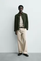 Sobrecamisa de hombre con cuello solapa, manga larga y cierre frontal de botonadura. Presenta un estampado de rayas verticales en tonos de verde oliva y verde oscuro. Incluye bolsillos plastrón en la cadera.