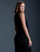 Enterito de lentejuelas marca Ninety, color negro, con escote en V cruzado y diseño sin mangas. Presenta cintura elastizada con lazo de ajuste, bolsillos frontales y abertura en la espalda con cierre invisible. Incluye forro interno a tono.