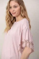 Remera de algodón color blanco, con cuello redondo y mangas cortas holgadas que presentan detalles de encaje broderie.