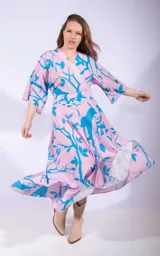 Vestido midi color lila con estampado de hojas turquesas, corte cruzado, mangas 3/4 y lazo en la cintura.