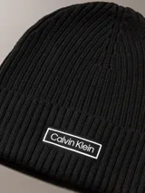 Gorro tipo beanie de punto grueso acanalado en color negro, con vuelta y parche rectangular con el logo de Calvin Klein en el frente.