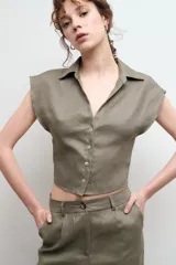 Camisa color beige claro de lino, con cuello clásico, abotonada al frente y sin mangas.